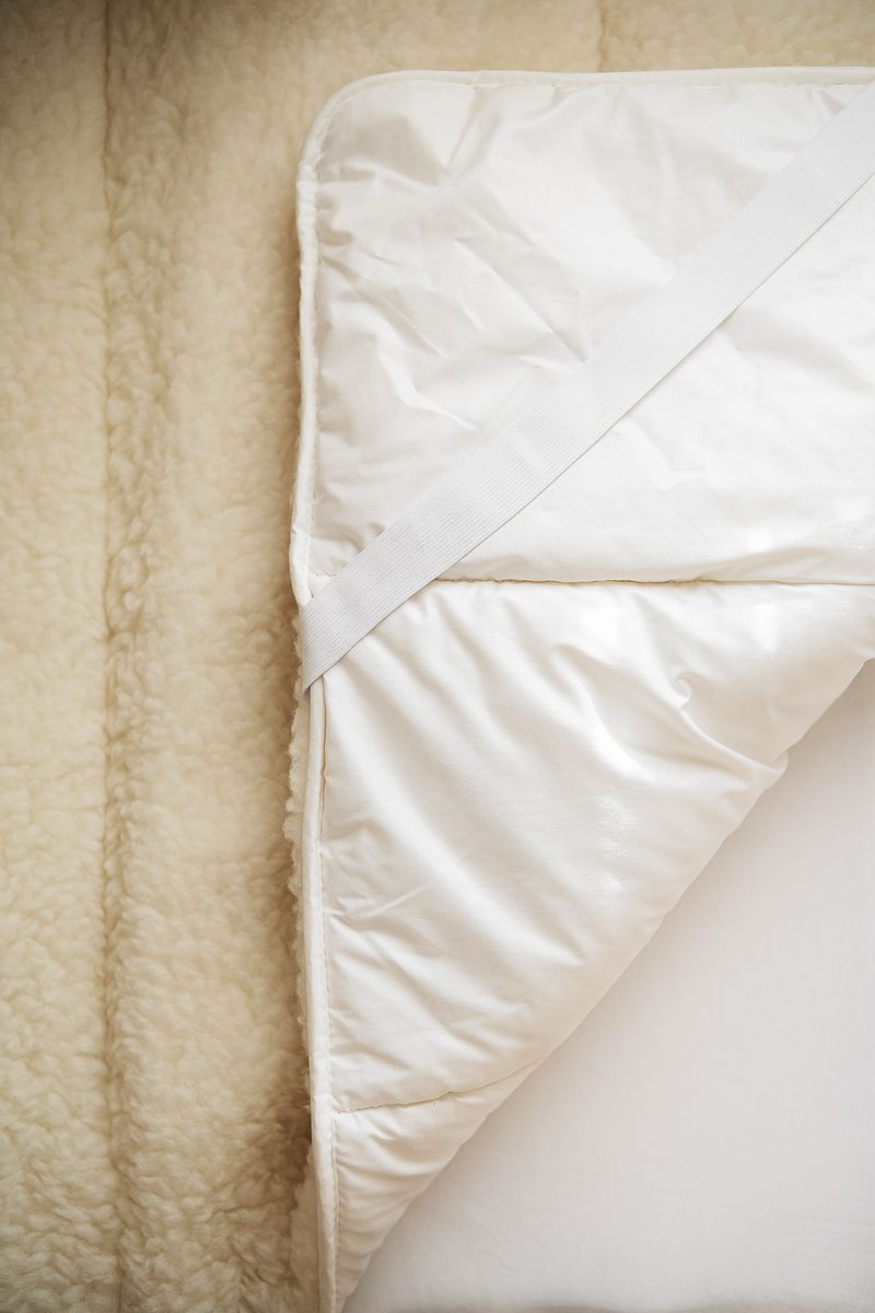 Close‑up van wollen matrastopper van Kico Label, naturel beige, met zichtbare wolstructuur