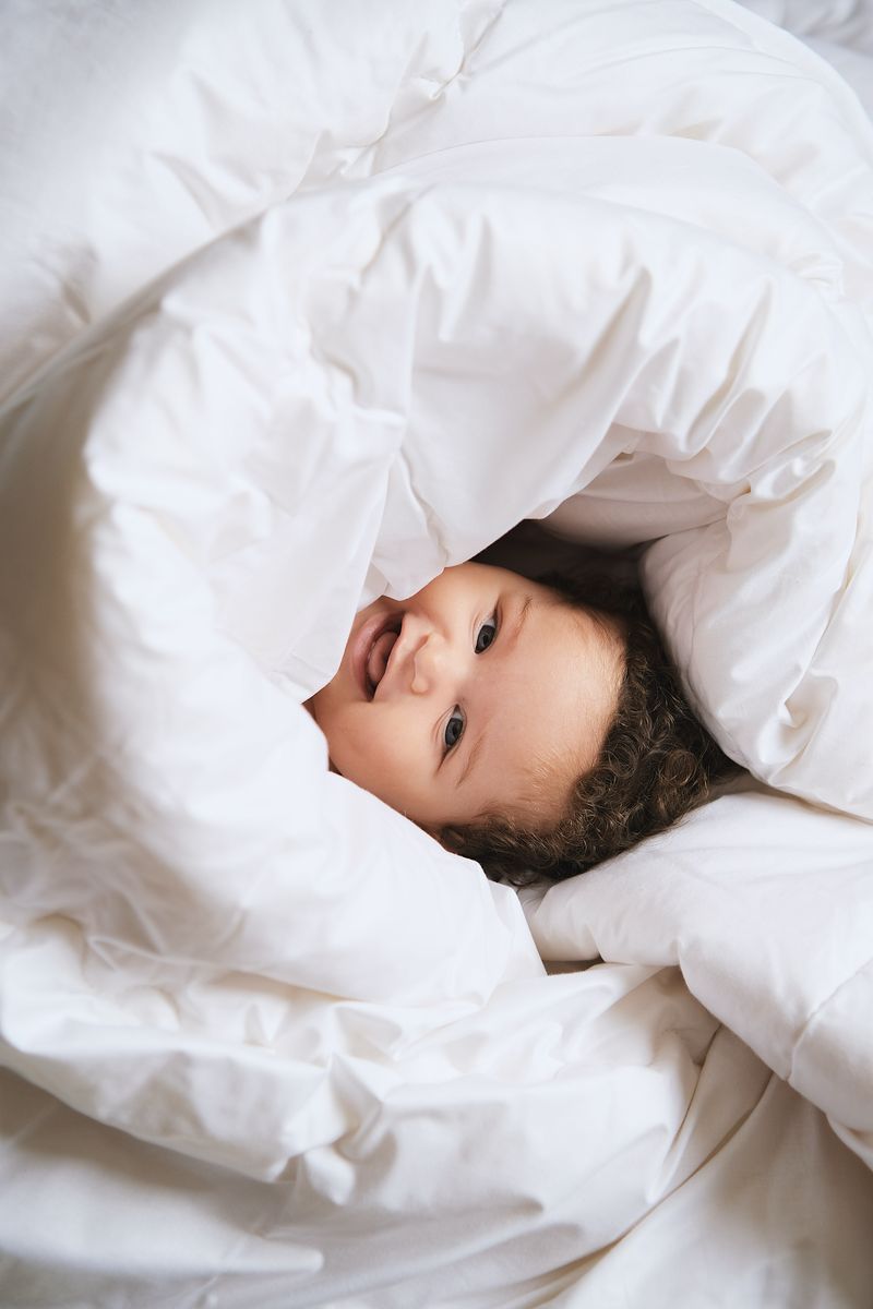 Baby ligt knus onder 100% merinowollen dekbed van Kico Label, zacht en ademend