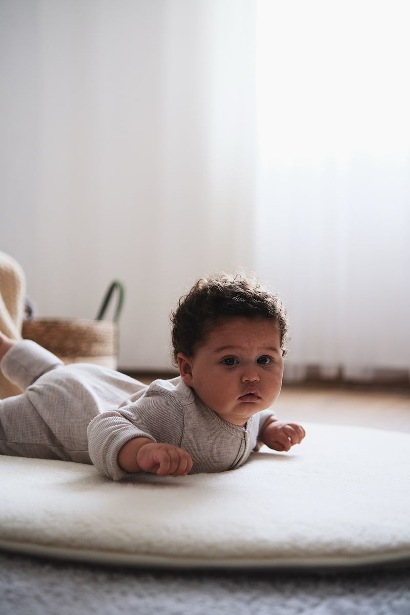 Baby ligt op rond boxkleed van naturel merinowol (90 cm)