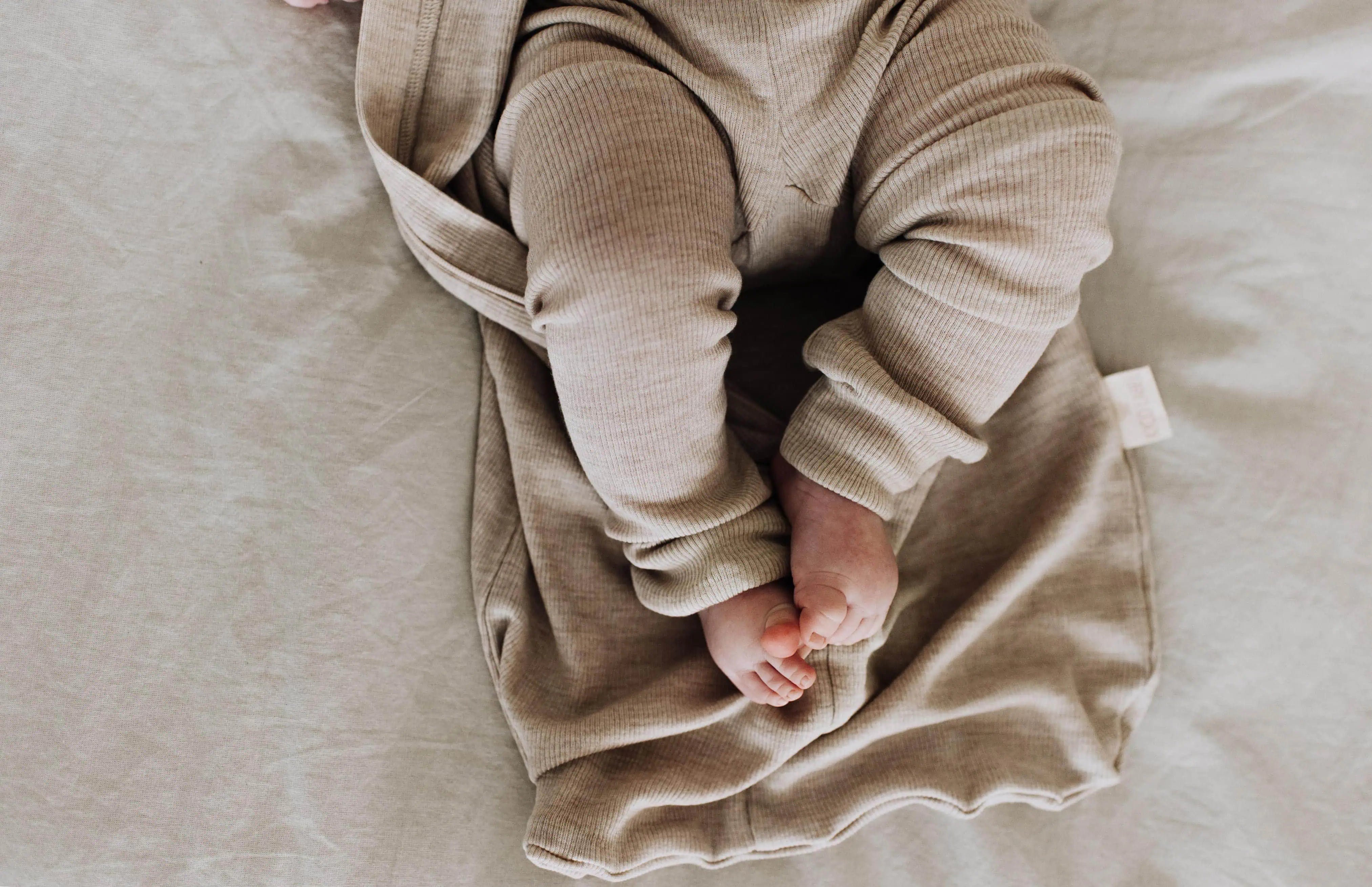 baby in wollen pyjama met ontblote voetjes