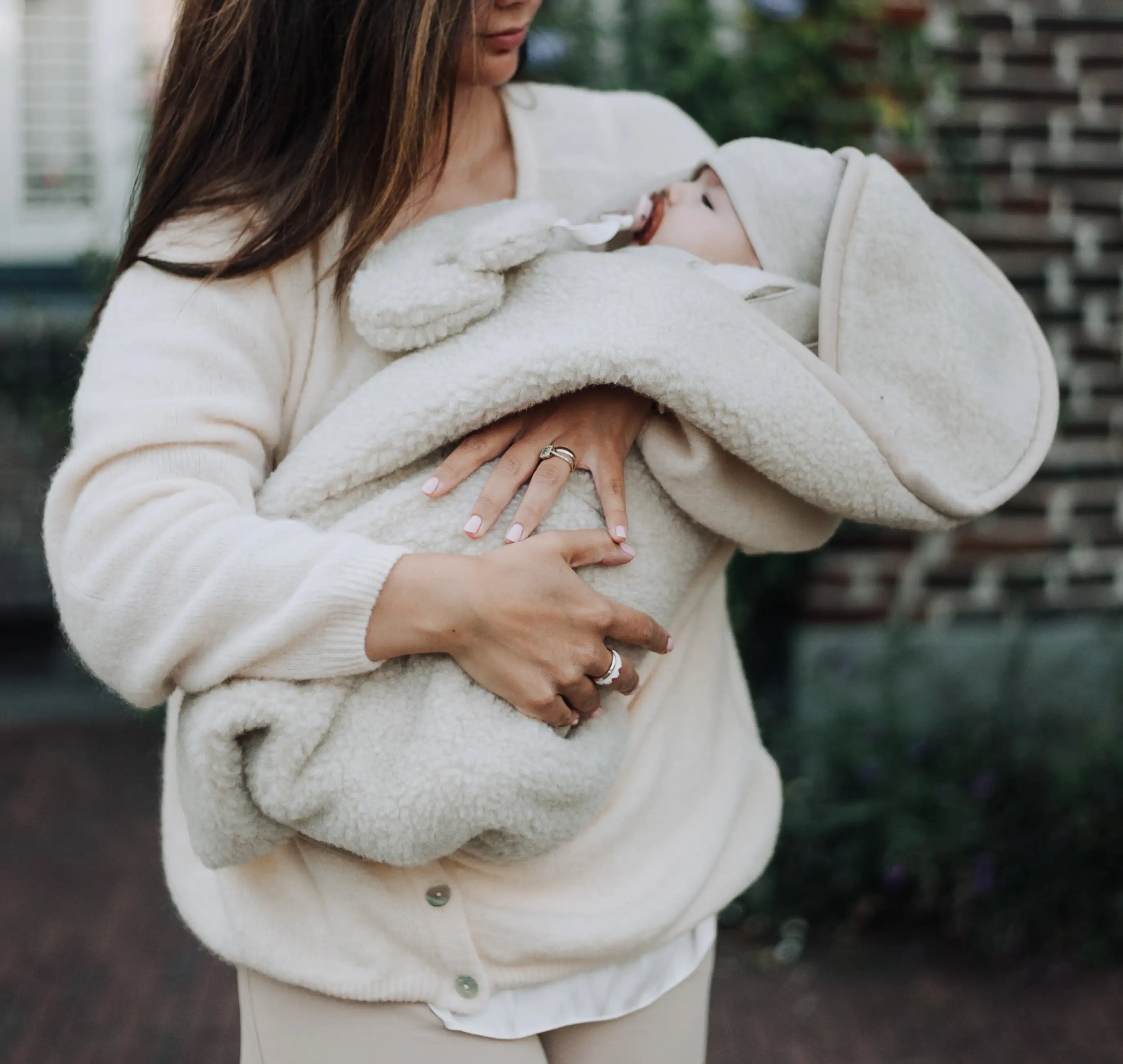 baby die wordt gedragen door de moeder. De baby is gewikkeld in een wollen wikkeldeken
