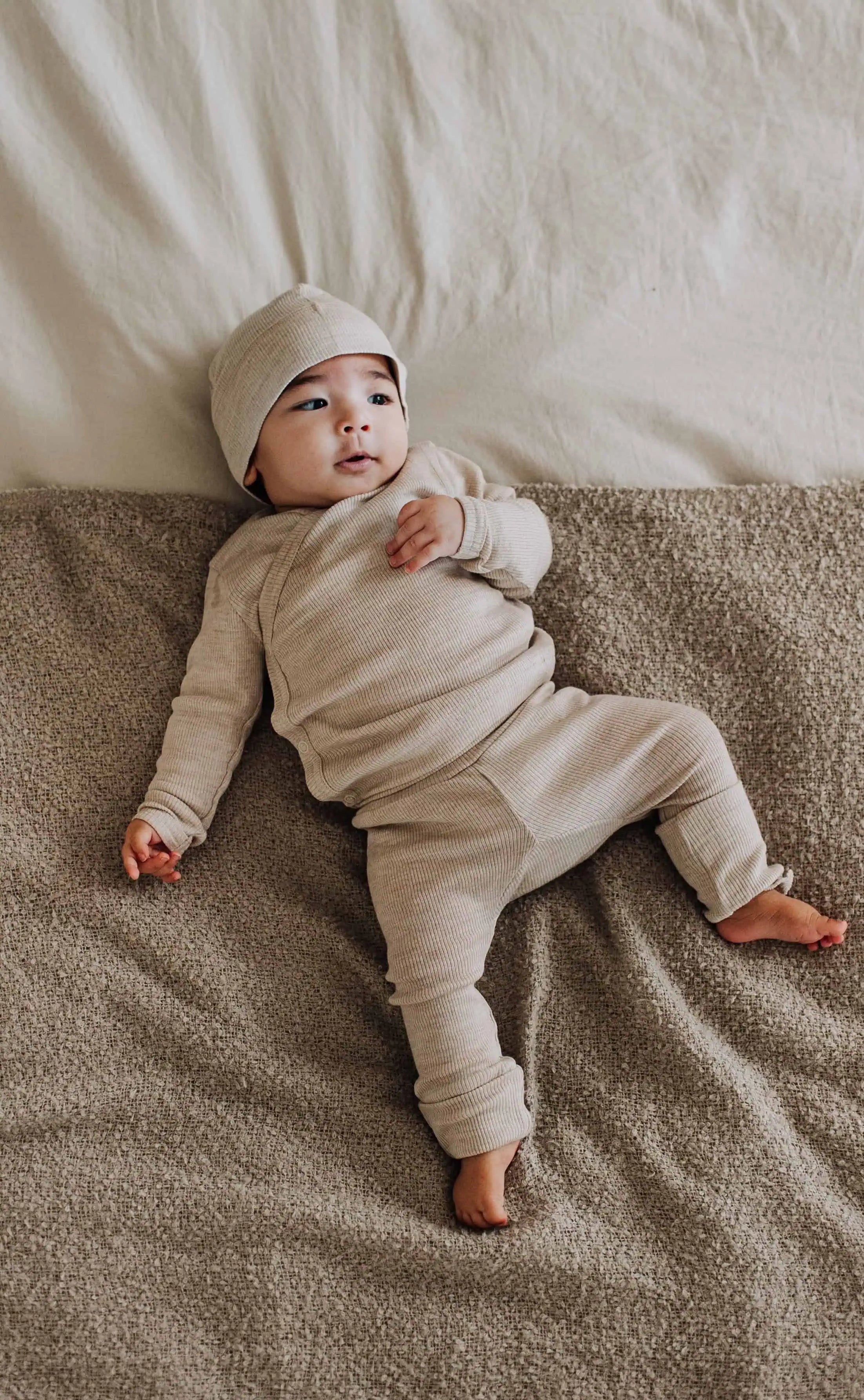 Baby met wollen overslag set op bed