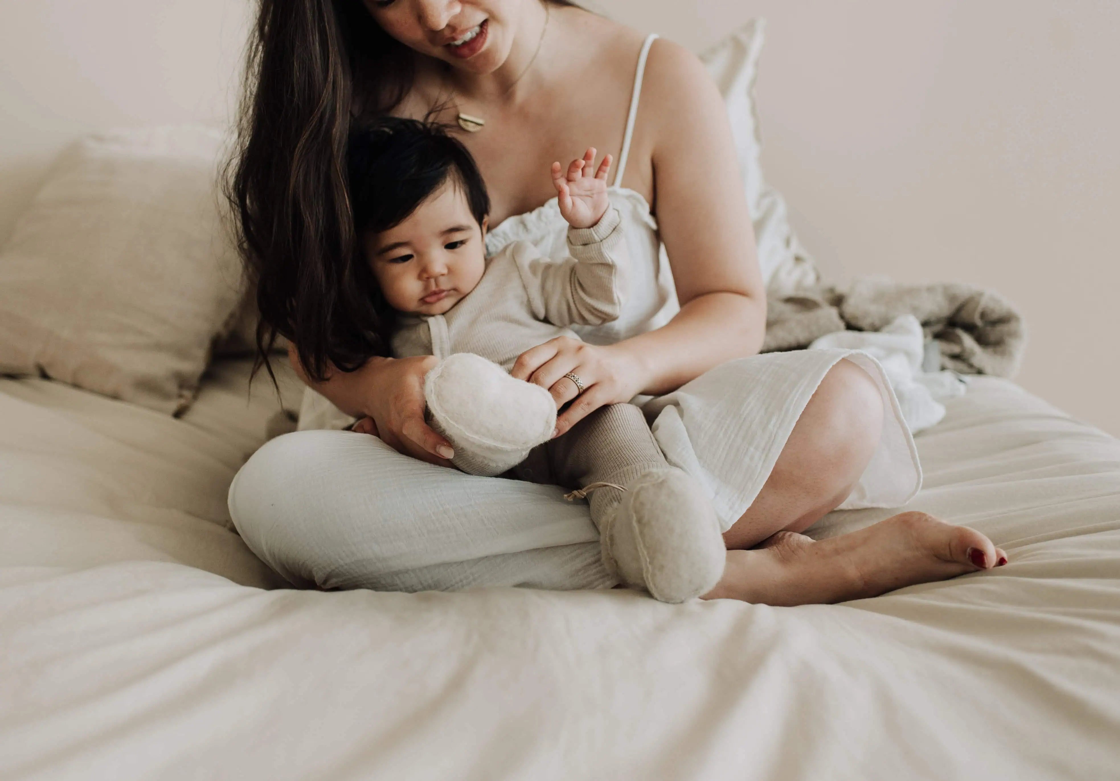 Baby en moeder op bed in beige kleding op een zondagochtend