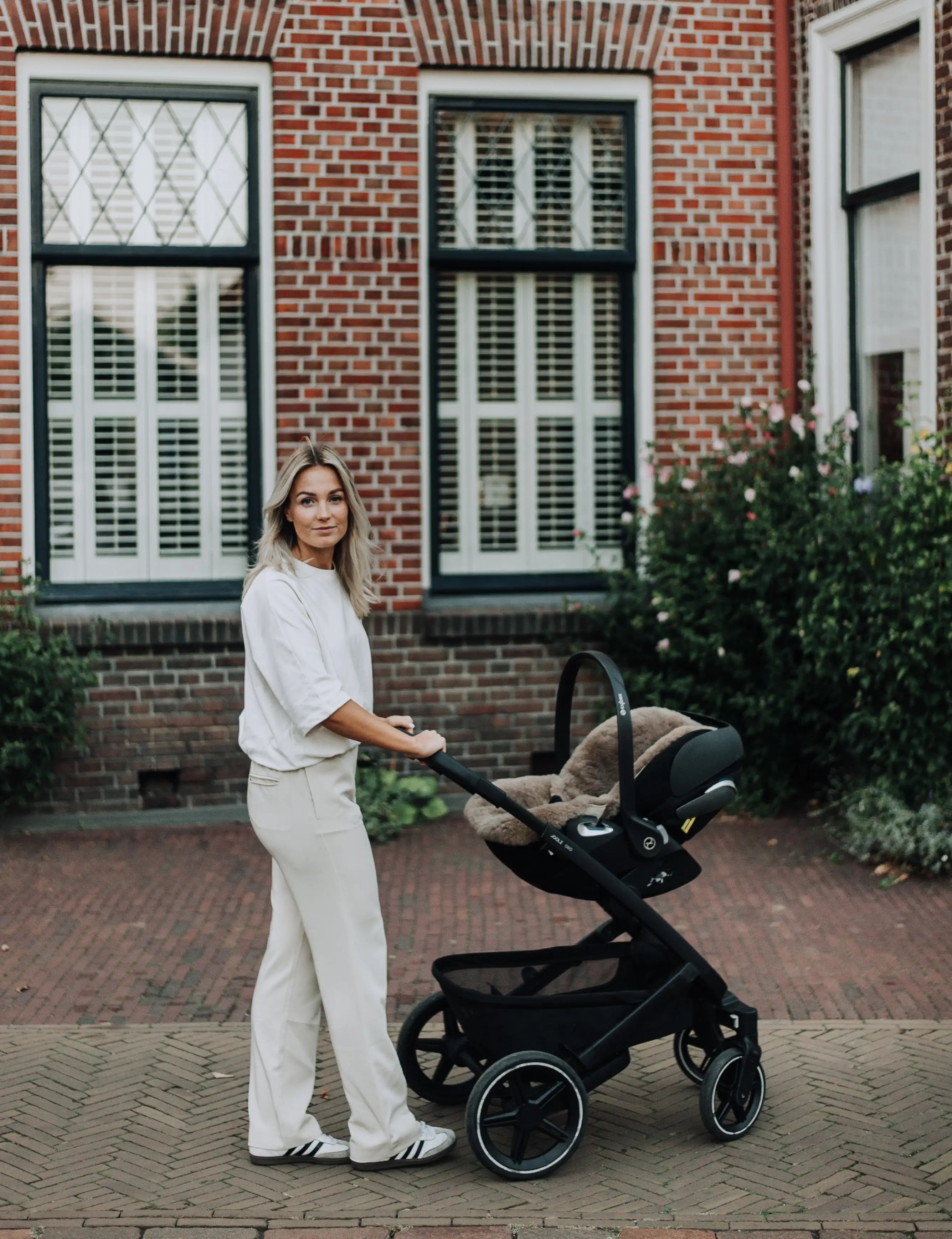 moeder achter een kinderwagen met daarin een wollen schapenvacht