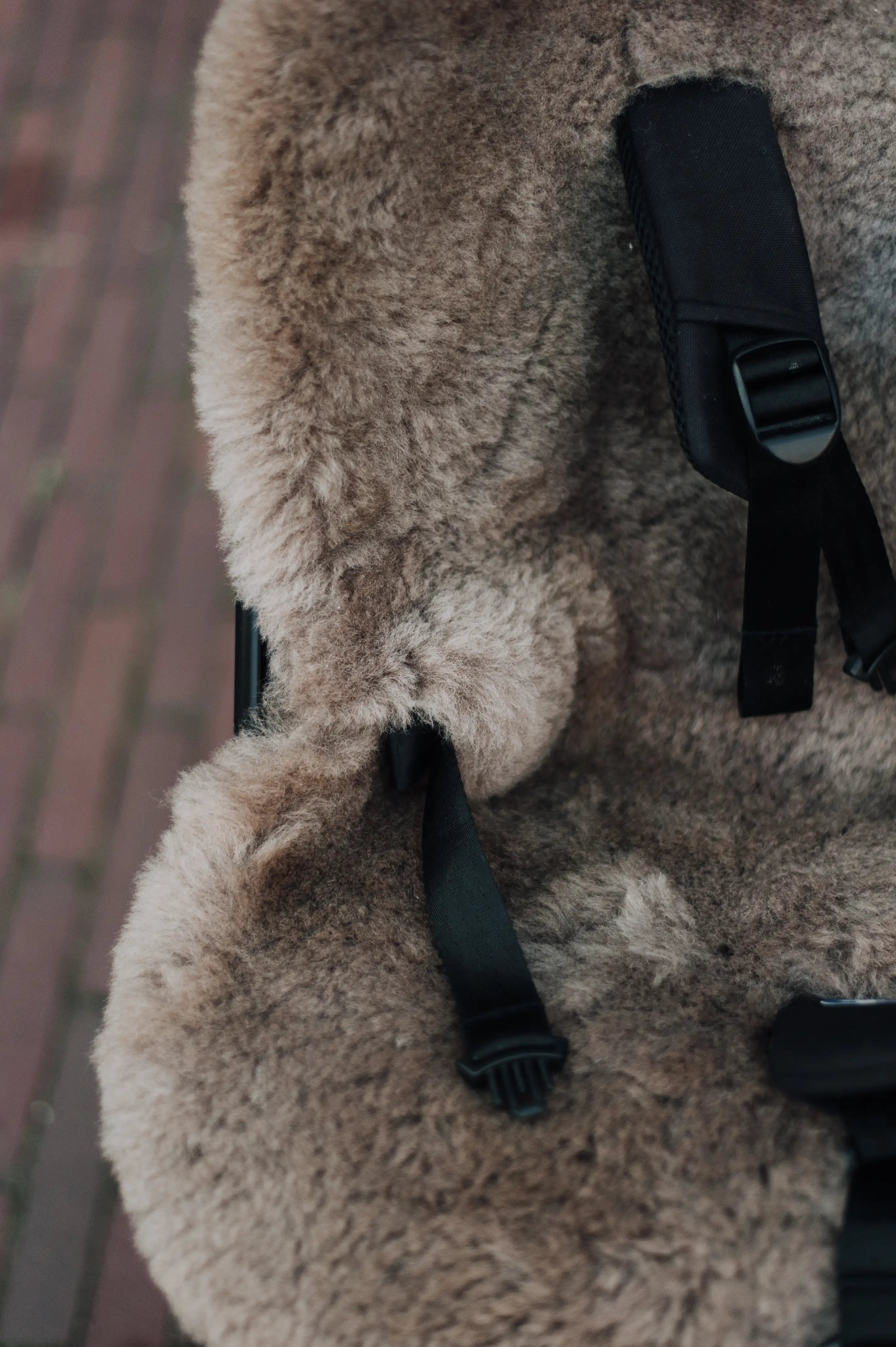 foto van een wollen schapenvacht waar de riempjes doorheen zijn gestoken waarin een baby / kind kan worden bevestigd