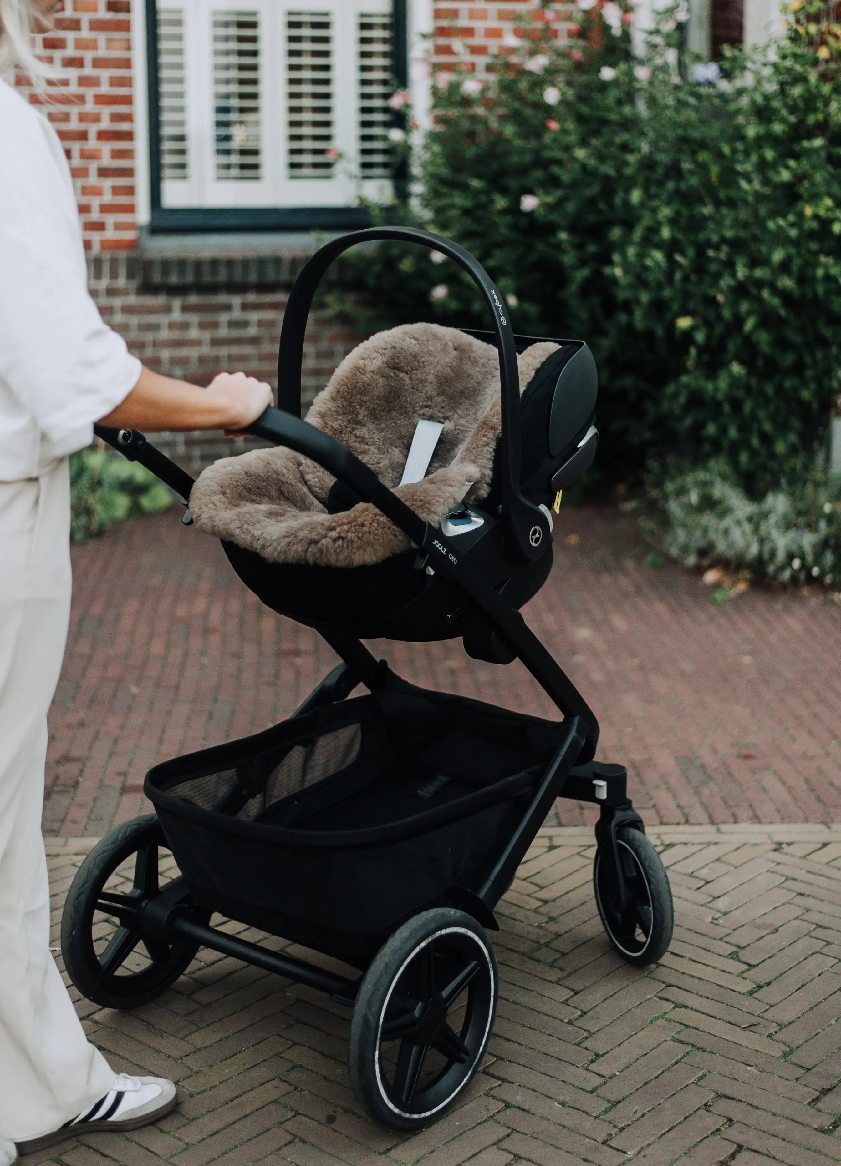 moeder achter een lege kinderwagen waar een schapenvacht van wol in ligt
